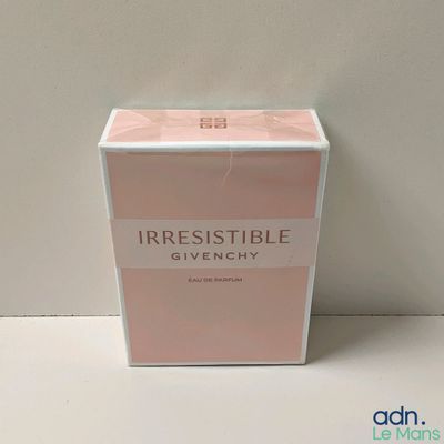 un flacon de parfum dans une boîte, posé sur une table avec un mur blanc en arrière-plan