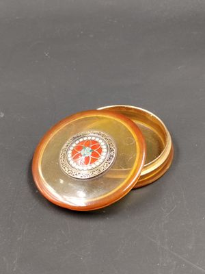 une petite assiette en or ornée d'une fleur rouge