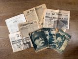 plusieurs vieux journaux posés sur une table en bois, avec une photo en noir et blanc d'un homme