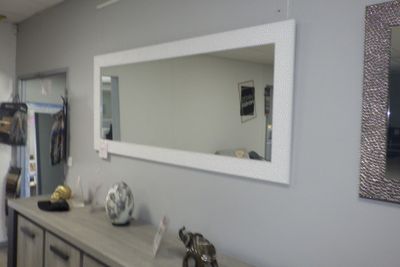 un miroir accroché au mur au-dessus d'une commode dans une pièce