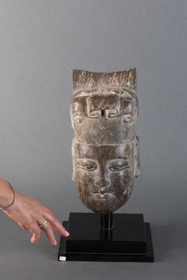 sculpture représentant la main d'une femme touchant une tête en pierre posée sur un socle noir