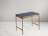 une table noire et dorée avec un plateau en verre, posée sur un socle blanc