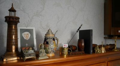 une étagère en bois sur laquelle sont posés une horloge, des vases et des photos