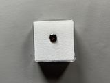 a close up of a small black diamond on a white surface