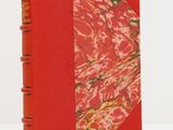 un vieux livre à la couverture rouge, orné d'un motif