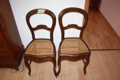 two wooden chairs sitting next to each other on a hard wood floor