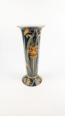 un vase bleu orné de fleurs jaunes sur fond blanc