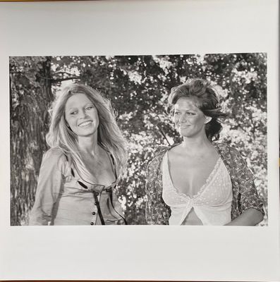 black and white photograph of two women standing next to each other in front of trees