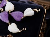 purple, white and gold necklace and earrings on a velvet case