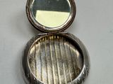 a silver pill case with a mirror in it