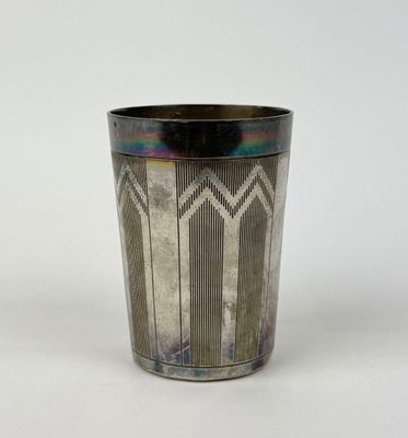a silver cup with a design on it on a white surface