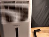 un climatiseur posé sur une table en bois, à côté d'un téléphone
