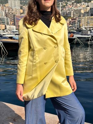 une femme vêtue d'un manteau jaune, debout au bord de l'eau