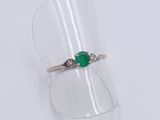 a close up of a ring with a green stone on top of a clear ring