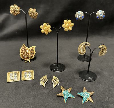 a group of earrings and brooches on display on a black background