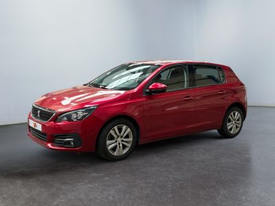 Une voiture rouge est garée dans une pièce aux murs blancs.