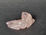 rose quartz crystal animal figurine on a black surface