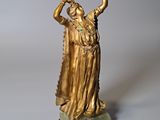 statue en or représentant une femme les bras levés vers le ciel