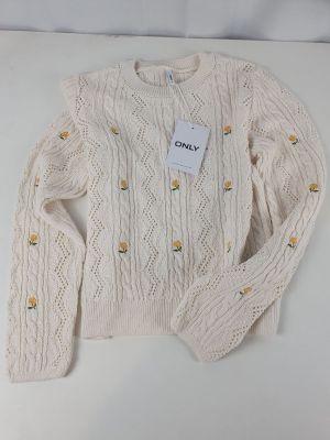 a close up of a white sweater with a tag on it