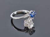 a close up of a diamond and sapphire ring on a black surface