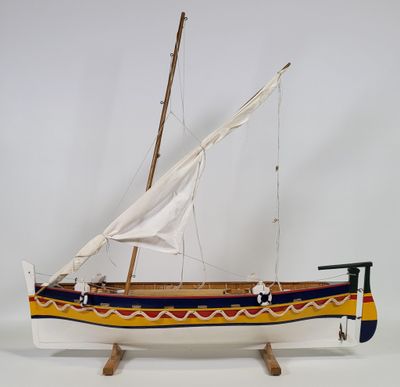 wooden model of a sailboat with a white sail on a wooden stand