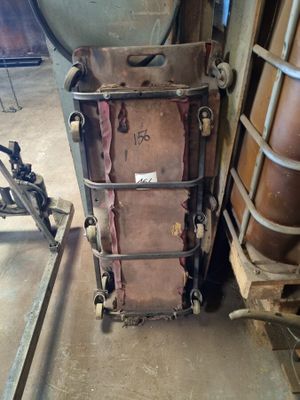 une vieille valise posée à côté d'un porte-vêtements en métal dans une pièce