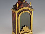 une petite horloge surmontée d'un miroir