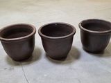 trois pots marron posés par terre dans une pièce