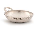an old silver bowl with a handle on a white surface