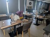 many tables and chairs in this restaurant with a clock on the wall