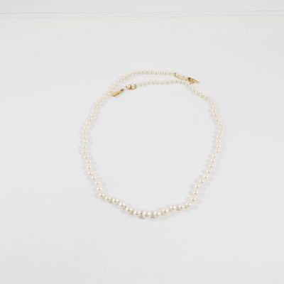 un collier de perles blanches avec un fermoir en or sur fond blanc