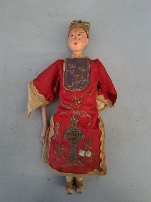 une vieille poupée vêtue d'une robe rouge et coiffée d'une couronne dorée