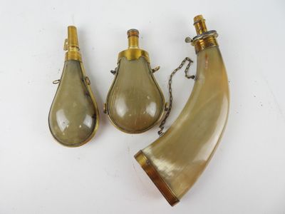 trois bouteilles en verre et une corne posées sur une surface blanche