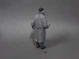 a man in a gray coat walking with a cell phone in his hand