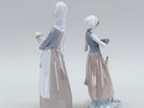 pair of porcelain figurines of two women with a basket of flowers