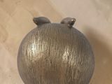 a metal sculpture of a pig sitting on top of a wooden table