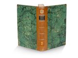 un vieux livre à la couverture verte posé sur une surface blanche