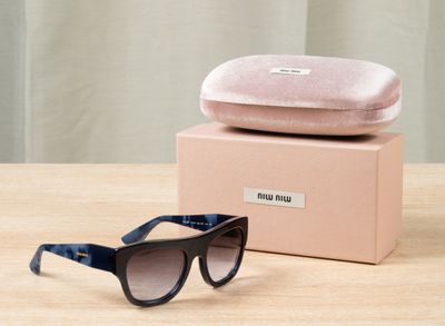 une paire de lunettes de soleil noires et bleues posée sur une table en bois