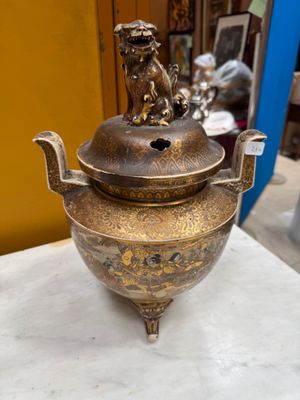 brass teapot with a lion on top of it on a table