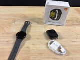 Une Apple Watch est posée sur une table en bois, à côté d'une boîte et d'un chargeur