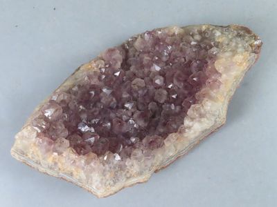 des cristaux violets et blancs posés sur un morceau de roche, sur une surface blanche