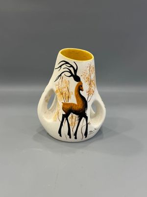 un petit vase orné d'un cerf, posé sur une table