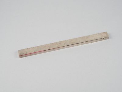 une règle posée sur une surface blanche, avec une ligne rouge