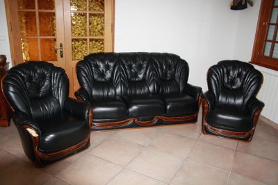 three black leather couches and two chairs in a living room