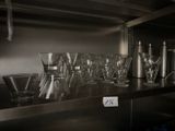 many glasses and cups on a shelf in the kitchen