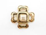 a close up of a gold cross brooch with a pearl center