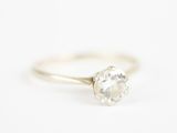 un gros plan d'une bague en diamant blanc posée sur une surface blanche