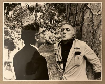 photographie en noir et blanc de deux hommes debout près d'un arbre