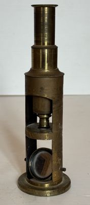 un vieux télescope en laiton avec une lentille noire posée sur une surface blanche