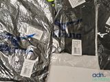 three pairs of shirts wrapped in plastic on a table